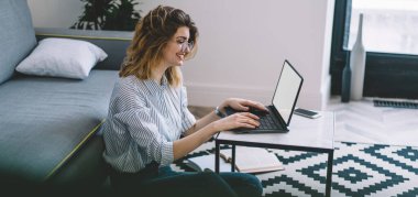 Ev internet bağlantısını kullanarak internet sitesinde komik yayınlar arayan, dizüstü bilgisayarında yazı yazan mutlu beyaz kadın, Netbook 'ta boş ekranla uzaktan çalışan neşeli hippi kız.