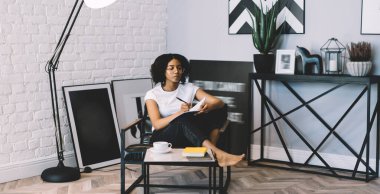 Yetenekli Afrikalı Amerikalı tasarımcı eğitim notlarında çizim yapıyor. Hafta sonları çatı katında ilginç projeler yaratıyor. Gözlüklü çekici bir kadın, kitaplarda yazı yazıyor.