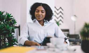 Siyah tenli Afro-Amerikalı yeniyetme kız moda haberleriyle ilgilenen gazeteden yeni bir yayın okuyor. Siyahi kadın genç, eğitim edebiyatıyla birlikte hafta sonunun keyfini çıkarıyor.