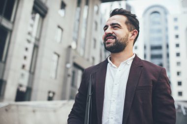 Resmi takım elbiseli, mutlu, zarif etnik bir adamdan. Evrak işleriyle uğraşan, zamanını şehir sokağında dikilip gözlerini kaçıran birinden.