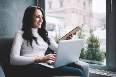 İyimser kadın serbest giyiniyor, gülümsüyor ve dizüstü bilgisayarla uzaktan kumandalı bir projede çalışıyor.