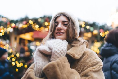 Sıcak kışlık giysiler giyen ve açık havada kışı geçirirken aydınlık kafeye karşı duran çekici bir kadının alçak açısı.