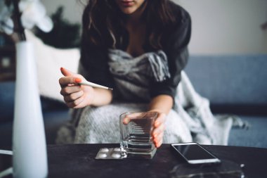 Konuşan bir kadının görüntüsü. Sıcaklığı ölçen, kötü hisseden, grip virüsünden muzdarip. Grip salgını.