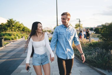 Randevu sırasında el ele tutuşup ilişki hakkında konuşan sıradan giyinmiş hippi erkekler. 20 yaşındaki genç bir erkek ve kadın. Romantik bir seyahat için hafta sonunun keyfini çıkarıyorlar.