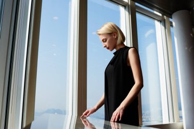 Siyah saçlı, güzel bayan işçinin interaktif bir masada interaktif bir şekilde internetten bilgi araması ve ara vermesi.