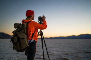 Çölde çekim yaptıktan sonra ABD 'de Badwater Havzası' nda seyahat eden kimliği belirsiz kadın fotoğrafçının fotoğrafları kontrol edişi.