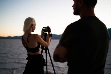 Akşam Badwater Havzası 'nda Ölüm Vadisi' ni keşfederken dağların fotoğraflarını çeken isimsiz yolcuların arka planı