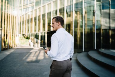Düşünceli iş adamının modern cep telefonu aygıtında kablosuz internet bağlantısı kullanmasının arka planı. Metropolitan City 'de yürüyen, dışarıda dijital akıllı telefon düşünen Kafkasyalı profesyonel çalışan.