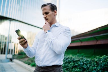 Resmi gömlek okuyan ciddi işadamı, bankacılık ödemelerinde şaşkınlık hisseden akıllı telefon e-postası aldı, Kafkasyalı erkek yönetici, internet sitesinde cep telefonu iletişimi kurma konusunda kafası karıştı