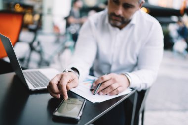 Bulanık iş adamı netbook teknolojisiyle kaldırım kenarında oturuyor ve cep telefonuyla mesajları kontrol ediyor. Hareketli sohbetler sırasında, yetenekli bir erkek, bankacılık için 4G 'ye bağlanıyor.