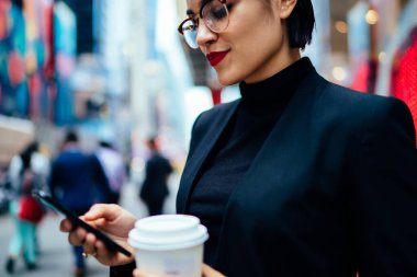 New York caddesinde ayakta dikilip haberleri okurken elinde bir fincan kağıt kahve ile başarılı bir kadın.