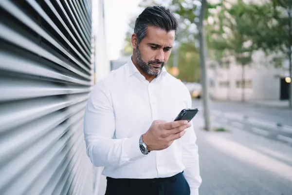 Successful male entrepreneur i white shirt using cellphone app for checking account balance, Caucasian businessman texting with colleagues via modern mobile technology connected to 4g internet