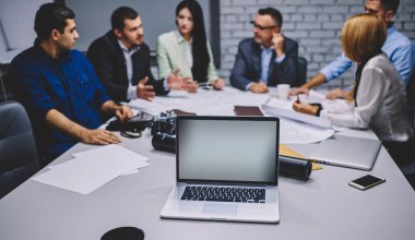 Profesyonel iş adamları toplantı masasında internet siteniz için ekran oluşturan dizüstü bilgisayarla iletişim kuruyor. Kopya alanı olan modern netbook teknolojisine odaklanıyor.