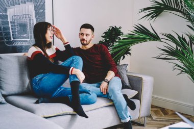 Beyaz tenli genç eş hafta sonu rahat koltukta dinlenirken iletişim kuruyor ve ev içi iç dekorasyon tarzını tartışıyor, karı koca çatı katında kaynaşırken ilişkiler hakkında konuşuyorlar.