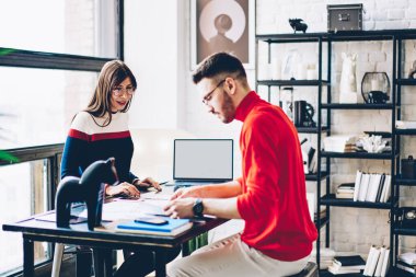 Genç girişimciler masaüstünde boş laptop teknolojisiyle işbirliği içinde beyin fırtınası yaparken projeyi tartışıyorlar, yetenekli grafik tasarımcılar web reklamcılığından ve taklit netbook için yer kopyalamaktan bahsediyorlar