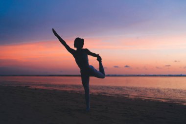 Antrenman sırasında farkındalık ve aydınlanma arayışı için Asana 'yı geren kadın silueti, deniz kıyısındaki yoga eğitimi sırasında rahatlamanın ve canlanmanın keyfini çıkaran sakin kadın.