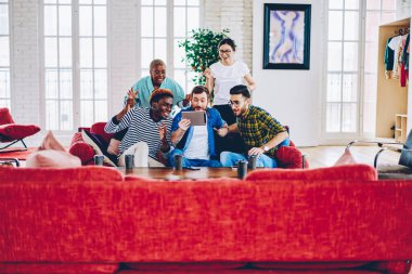 Gündelik giyinmiş duygusal hipsterlar zaferi kutlarken dijital tabletten canlı yayın izliyorlar. Modern apartman dairesinde hafta sonu 4G internet kullanıyorlar. Spor bahisleri ve başarı.
