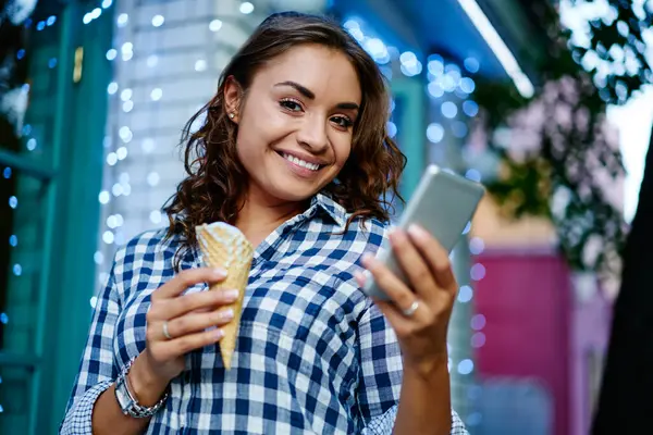4Gインターネットに接続された携帯電話を介してアイスクリームやウェブメッセージを楽しんで笑うスタイリッシュなアパレルで幸せなティーンエイジャー ジェラートソーベットと現代携帯ガジェット笑顔 ロイヤリティフリーのストック画像
