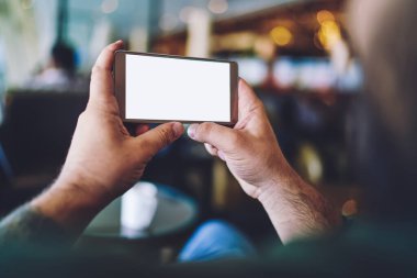 Dinlenme ve dinlenme alanında video izlerken yüzü olmayan bir adamın akıllı telefonu yatay pozisyonda tutuşu.