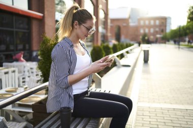 Milenyum hippi kızı optik gözlüklü cep telefonu aygıtını şehirdeki boş zamanlarında internette arama ve mesajlaşma için kullanıyor. Kafkas kadın blogcu uygulama ve aygıt üzerindeki bildirimi kontrol ediyor.