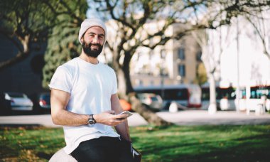 Moda giyinmiş Türk blog yazarının yarısı elinde dijital cep telefonu teknolojisiyle turistik kenti ziyaret ederken kameraya bakıyor, cep telefonu pozu veren Orta Doğulu erkek kullanıcı