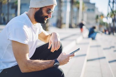Güneş gözlüklü Orta Doğulu bir adam cep telefonu teknolojisiyle gelen kısa mesajları okuyor, sakallı hippi telefon ediyor ve mobil sohbet yapıyor. İnternetten rezervasyon yapmak için uygulama kullanıyor.