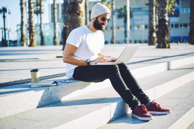 Günes gözlüklü Türk erkek blogcu, kentteki modern dizüstü bilgisayar cihazını kullanarak internet sitesinde boş zaman ağı arayışı içinde, netbook sohbetleri sırasında mesaj yazan yetenekli hippi.