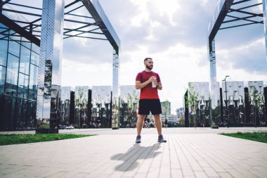 Koşu yaptıktan ve sabahın erken saatlerinde eğlenirken elinde şişe olan erkek sporcunun boyu.