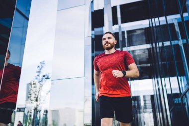 Şehir merkezinde tek başına egzersiz yapmadan önce aktif giyimli kendine güvenen bir adamın kaslarını ısıtmasından.