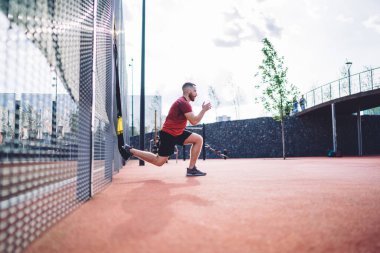 Spor ayakkabılı kararlı sporcunun sabahın erken saatlerinde TRX kayışlarıyla antrenman yaparken başını çevirmesi ve ısınması.