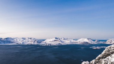 Kışın karla kaplı görkemli fiyort dağlarının nefes kesici kuş bakışı görüntüsü. Hava manzaralı kaya zirveleri, resim gibi güzel doğa manzarası. Lofoten Adası İskandinav Denizi ile çevrilidir