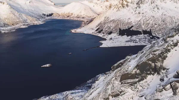 Kışın karla kaplı görkemli fiyort dağlarının nefes kesici kuş bakışı görüntüsü. Hava manzaralı kaya zirveleri, resim gibi güzel doğa manzarası. Lofoten Adası İskandinav Denizi ile çevrilidir