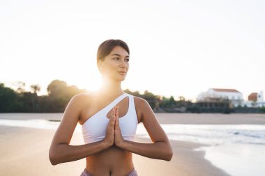 Sabah sahili sahilindeki yoga sırasında harmoni ve meditasyon eğitimi, spor kıyafetleri içinde dalgın bir kadın Asya 'da vücut konsantrasyonu için aerobik pilates yaparken namaste pozu vererek dua ediyor.