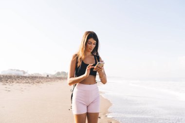 Sosyal ağlarda sohbet etmek ve mesajlaşmak için hücresel aygıt kullanan çekici kadın seyahat blogcusu, günlük giyimli genç beyaz kız web içeriğini taramak için 4G kablosuz ağa bağlanıyor