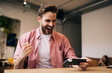 Modern joypad teknolojisini kullanarak online yarışmada zaferi kutlayan beyaz erkek, boş zamanlarında konsol kumandasında video oyunu seviyesini kazanırken sevinen milenyum adamı heyecanlandırıyor.