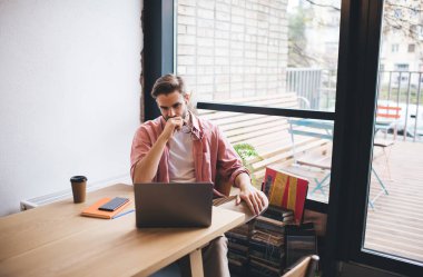 Bluetooth kulaklıklı Kafkas yazılım geliştirici, uzaktaki iş sırasında birlikte çalışan WIFI internet bağlantısını kullanarak modern netbook cihazında webinar videosu izliyor, veri kodlarını analiz eden yetenekli programcı