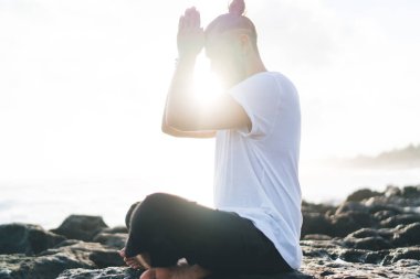 Kafkasyalı bir adam Asya 'da oturmuş yaşam enerjisi, rahatlık ve sükunet eğitimi alıyor. Nilüfer çiçeğinde meditasyon yapan sakin bir erkek kıyı şeridinde sağlık için yoga yapıyor.