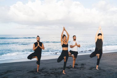 Eşofmanlı kadın ve erkek, yoga pozisyonunda meditasyon yapıyor. Deniz kıyısında nefes alıyor ve eğleniyor. Esnek insanlar, Asya 'da ilham ve dengeyi hissediyorlar.