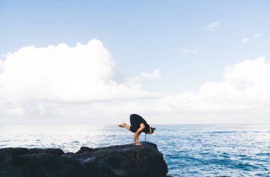 Sportif giyimli beyaz bir adam sağlıklı yaşam ve sağIık için yoga egzersizleri yapıyor. Erkek sporcu sabah antrenmanlarında ısınıyor ve sahil şeridinde el ele tutuşuyor.