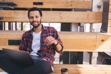 Neşeli milenyum insan programcısının portresi Netbook 'ta uzaktan çalışıyor serbest yaşam tarzının tadını çıkarıyor, mutlu hipster adam bilgisayardaki yazılımı güncellerken kameraya gülümsüyor 4G kablosuz kullanıyor.