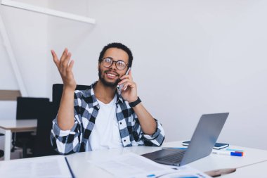 Optik gözlüklü mutlu bir çalışan, şirket ofisinde iş görüşmeleri için mobil cihaz kullanıyor, netbook ile gülen bir yönetici, telefonda iş organizasyonunu tartışıyor.
