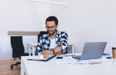 Görüş düzeltmesi için optik göz giyimi alanında mutlu bir erkek analist masaüstü bilgilendirme belgelerini modern laptop teknolojisiyle kontrol ediyor gözlük okuma stratejisi alanında yetenekli bir çalışan.