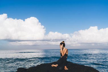 Sabah pilates yaparken vücut kaslarını esneten, okyanus manzarası yakınında meditasyon yapan, sağIıklı yaşam tarzını geri çekilme eğitimine devam eden sağlıklı kadın yogiler.