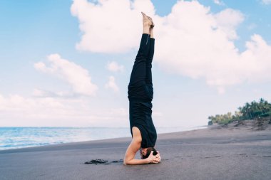 Güçlü erkek atlet, deniz kıyısı sahilinde sabah antrenmanı yaparken, beyaz adam, vücut şeklini mükemmel tutmak için yoga asana yapıyor ve sabah sporunun tadını çıkarıyor.