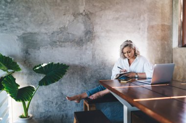 Kafkas kız öğrenci kapalı alanda öğrenim görürken ders kitabında eğitim notları yazıyor, yeni başlatılan proje üzerinde uzaktan çalışırken dizüstü bilgisayar ve dizüstü bilgisayar kullanarak özgür yazarlık yapıyor.