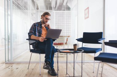 Sosyal medyada dizüstü bilgisayarı kullanarak video webinar 'ı izleyen yetenekli bir çalışan, dijital netbook üzerinden 4G kablosuz internete bağlanan milenyum erkek bilişim uzmanı.