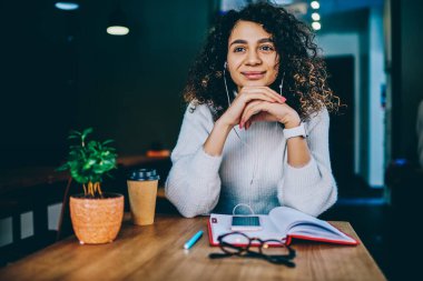 Cep telefonu ve kitaplarıyla kahve dükkanında dinlenen, kulaklıkla yüksek sesli medya çalma listesiyle eğlenen, elektronik kulaklıkla ses kaydını dinleyen genç hippi kız.