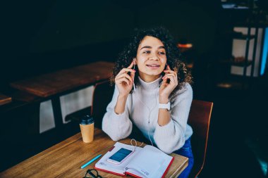 Akıllı telefonu ve kitaplarıyla kahve dükkanında dinlenen, kulaklıkla yüksek sesli medya çalma listesiyle eğlenen, elektronik kulaklıkla ses kaydını dinleyen genç hippi kız.