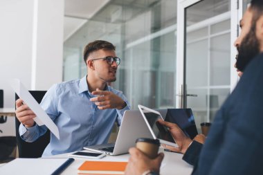 Bir grup profesyonel çalışan, ofis içi çalışma günlerinde kağıt raporlarını tartışırken, başarılı meslektaşlar, beyin fırtınası ile ilgili belgeleri incelerken, başlangıç projesinde işbirliği yapıyorlar.