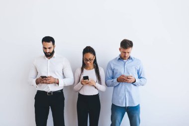 Akıllı gündelik kıyafet giyen çok ırklı iş arkadaşları cep telefonu mesajlaşması sırasında canlı iletişimi görmezden geliyor, iş bilgilerini kontrol eden çeşitli ortaklar web rezervasyonları ve bankacılık yaparken